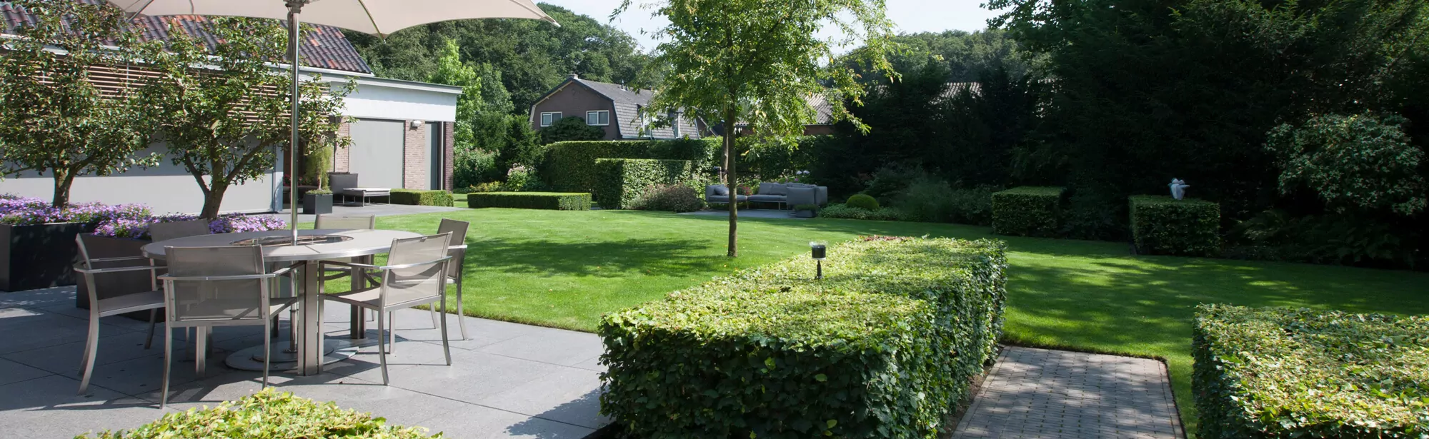Strakke moderne tuin met terras, gazon en geschoren hagen